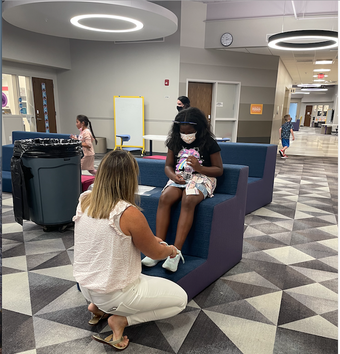 Board of Education member Jessica Tyndall helps third grader Laniai Cartwright tie her shoe. SUBMITTED PHOTO